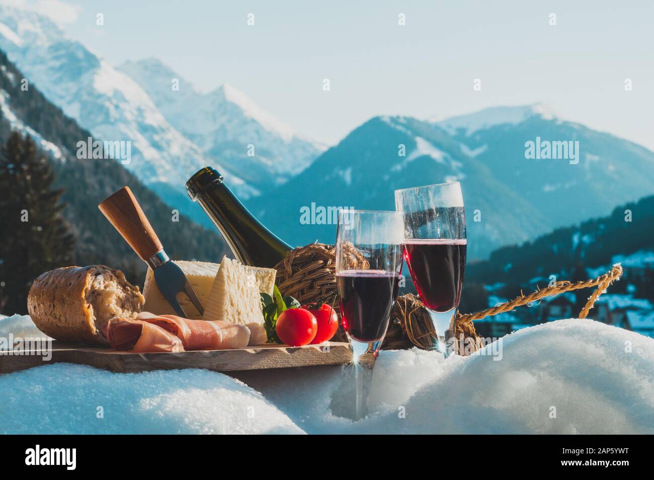 Cucina tradizionale italiana e bevande all'aperto nella soleggiata giornata invernale presso la stazione sciistica. Romantico pic-nic alpino nelle Dolomiti con sfondo montano Foto Stock