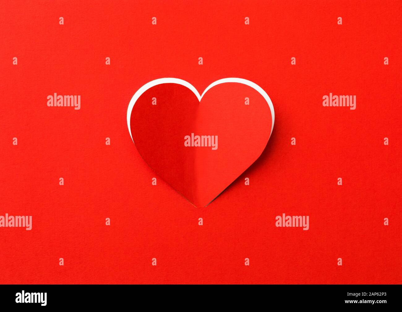 Il giorno di San Valentino sfondo. In rosso di un foglio di carta con un taglio fuori del cuore. Sfondo bianco. Foto Stock