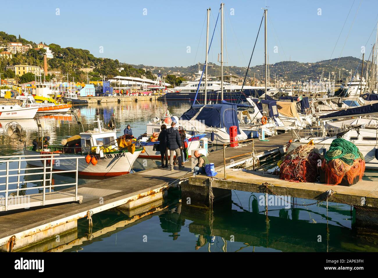 Persone in attesa di acquistare pesce direttamente da un pescatore su un molo del porto in una giornata di sole, Porto Maurizio, Imperia, Liguria, Italia Foto Stock