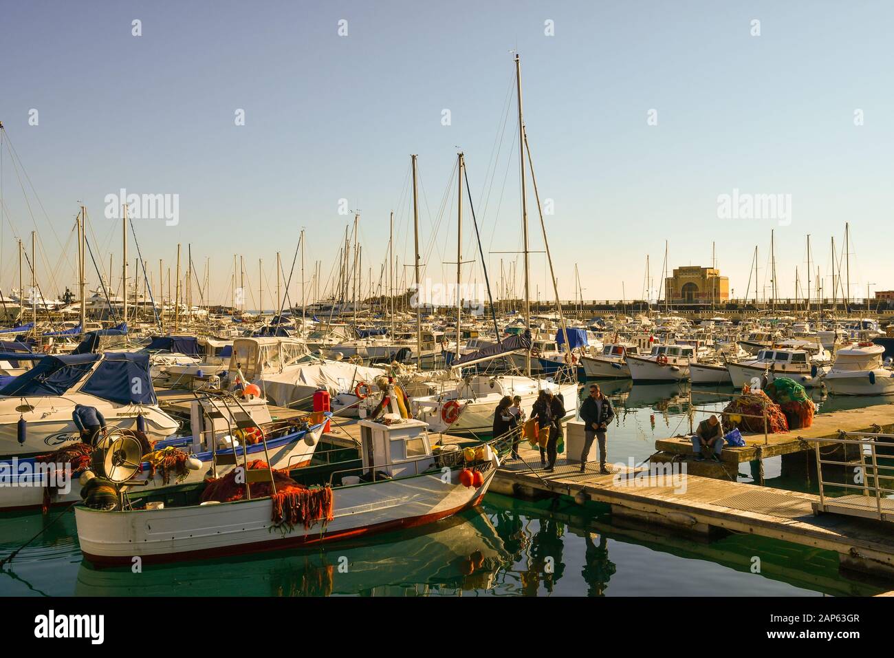 Persone in attesa di acquistare pesce direttamente da un pescatore su un molo del porto in una giornata di sole, Porto Maurizio, Imperia, Liguria, Italia Foto Stock