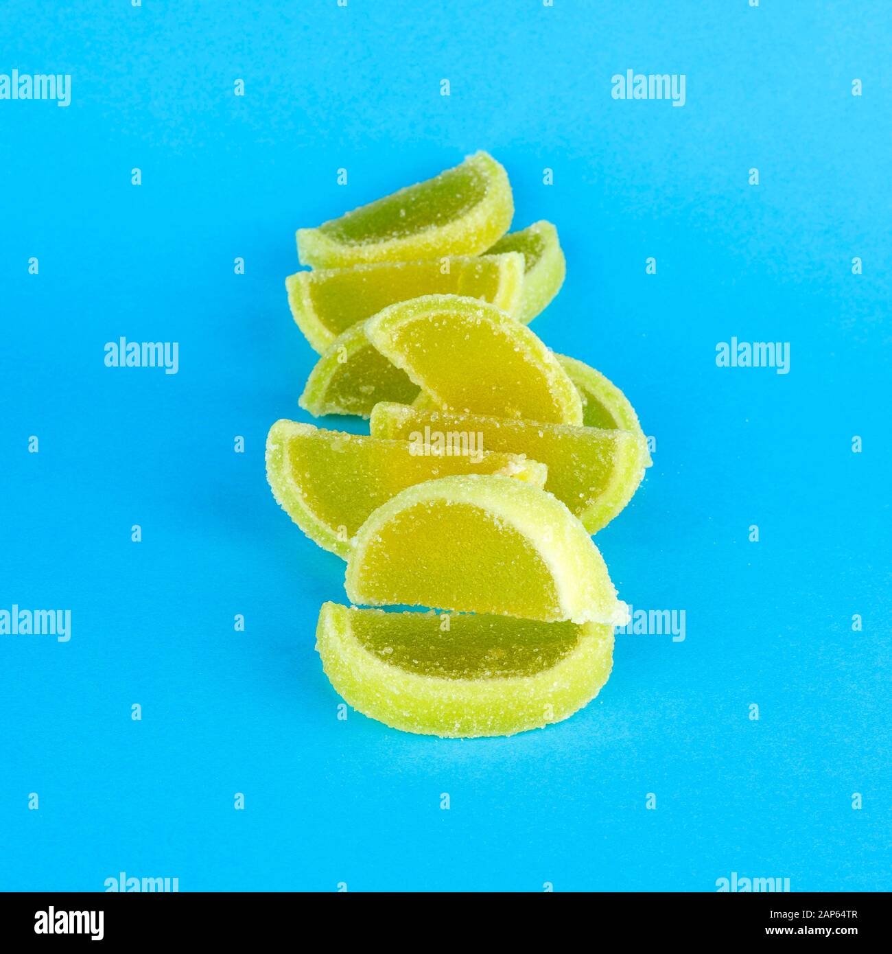 Caramelle di zucchero di gelatina colorate sotto forma di fette di limone e arancio isolato su sfondo blu. Foto Stock