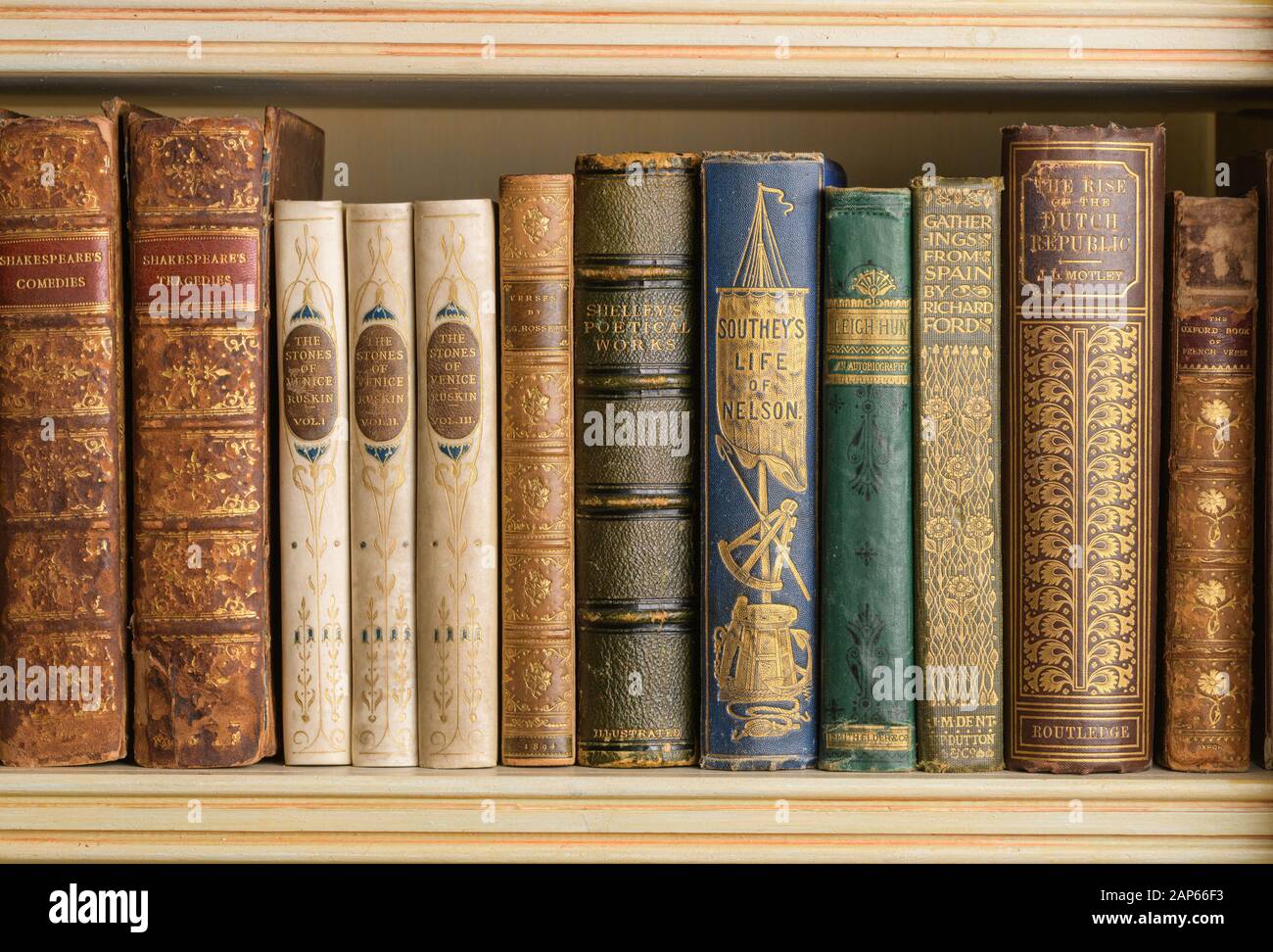 Fila di libri antiquari su una mensola di libro compreso le opere da Shakespeare, John Ruskin e Shelley Foto Stock