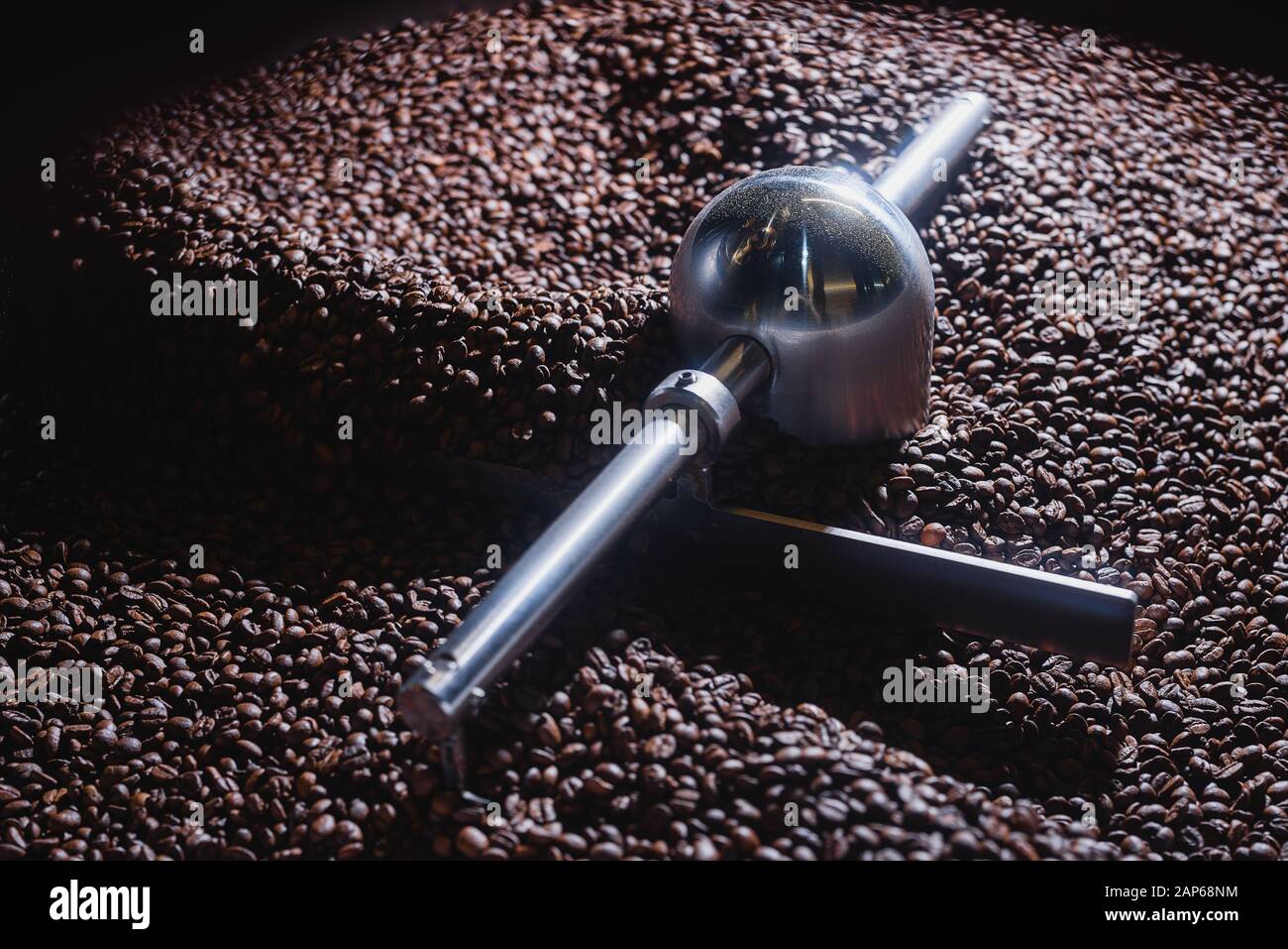 Processo di tostatura del caffè. Chicchi di caffè spostati dalla pala rotante all'interno della tramoggia per il raffreddamento e la vagliatura dopo la tostatura. Tipo di tamburo arrosto Foto Stock