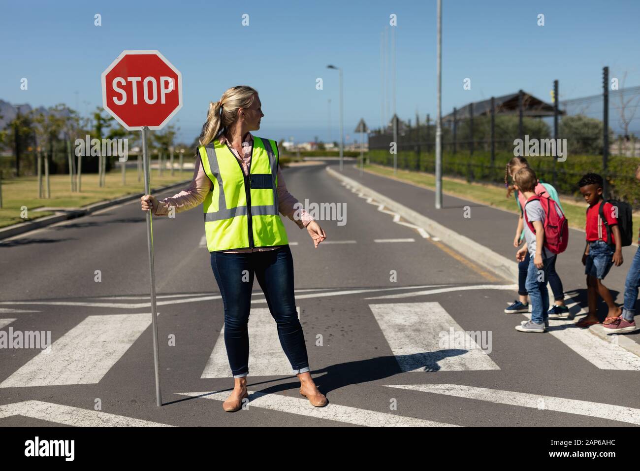 Donna che indossa un giubbotto ad alta visibilità e che tiene un cartello di stop Foto Stock