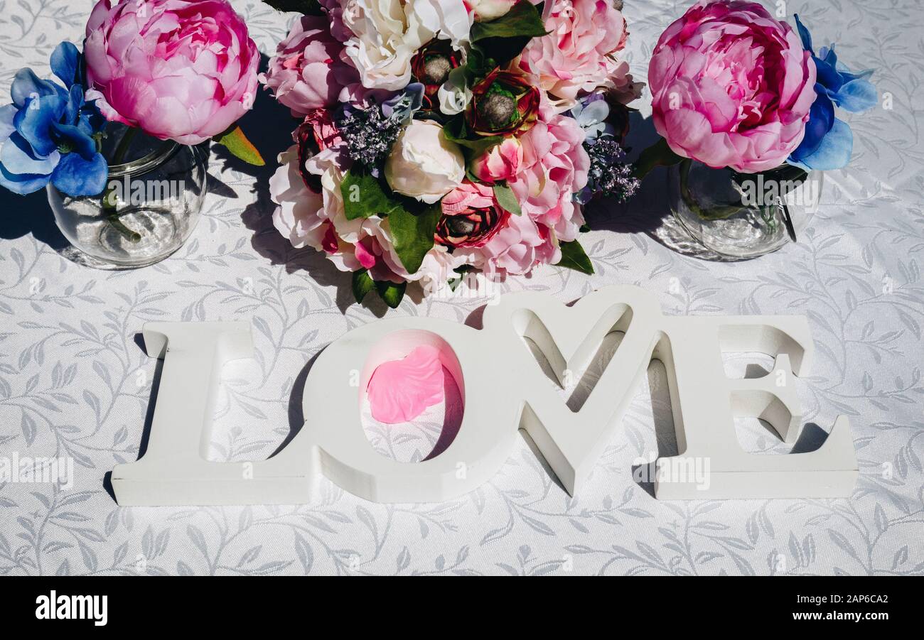 Layout creativi con fiori colorati, foglie e la parola AMORE. Il concetto di amore. Foto Stock