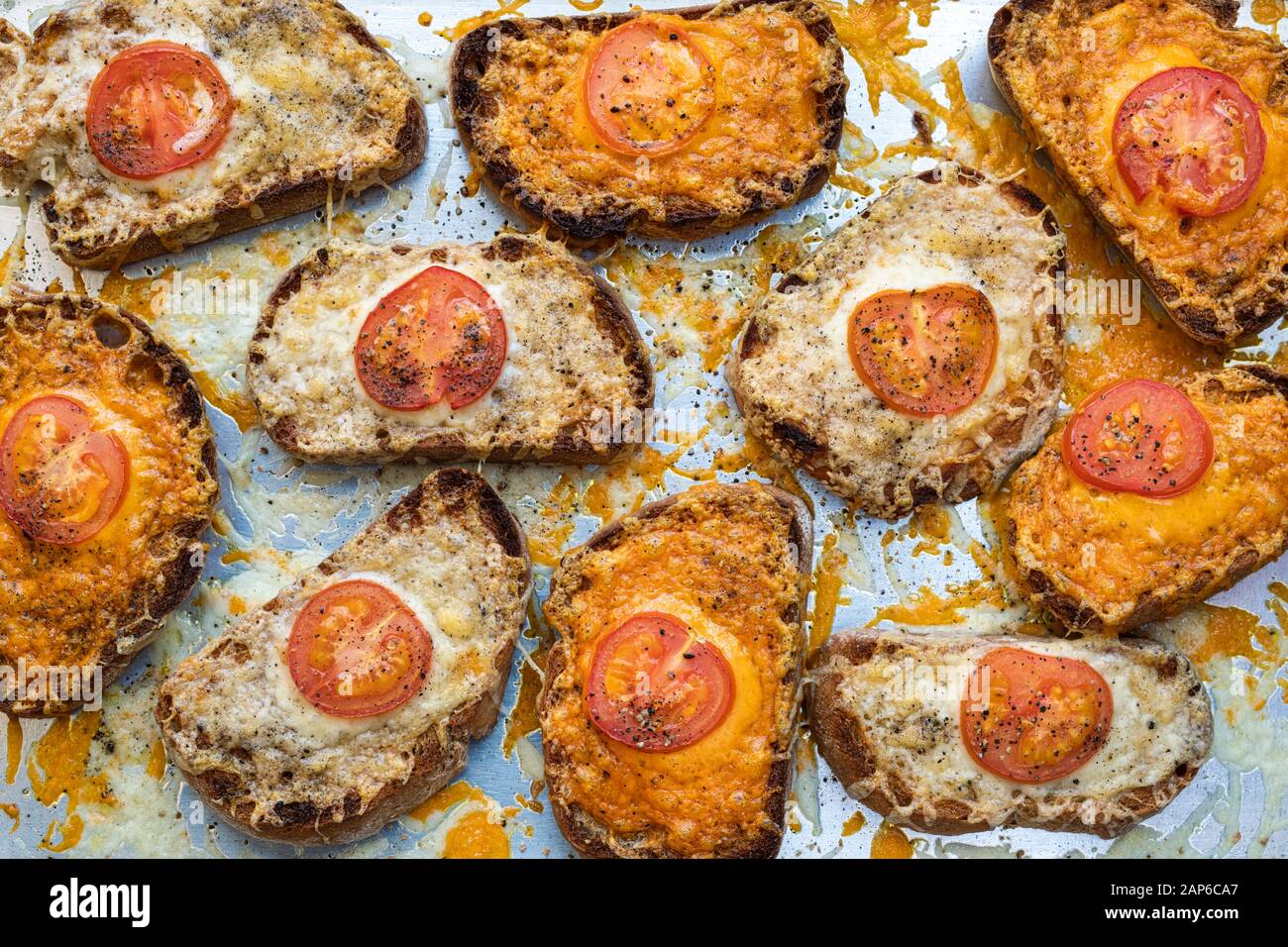 Chesse sul pane tostato. Pomodoro e formaggio sulla pasta madre tostati pane su un vassoio da forno Foto Stock