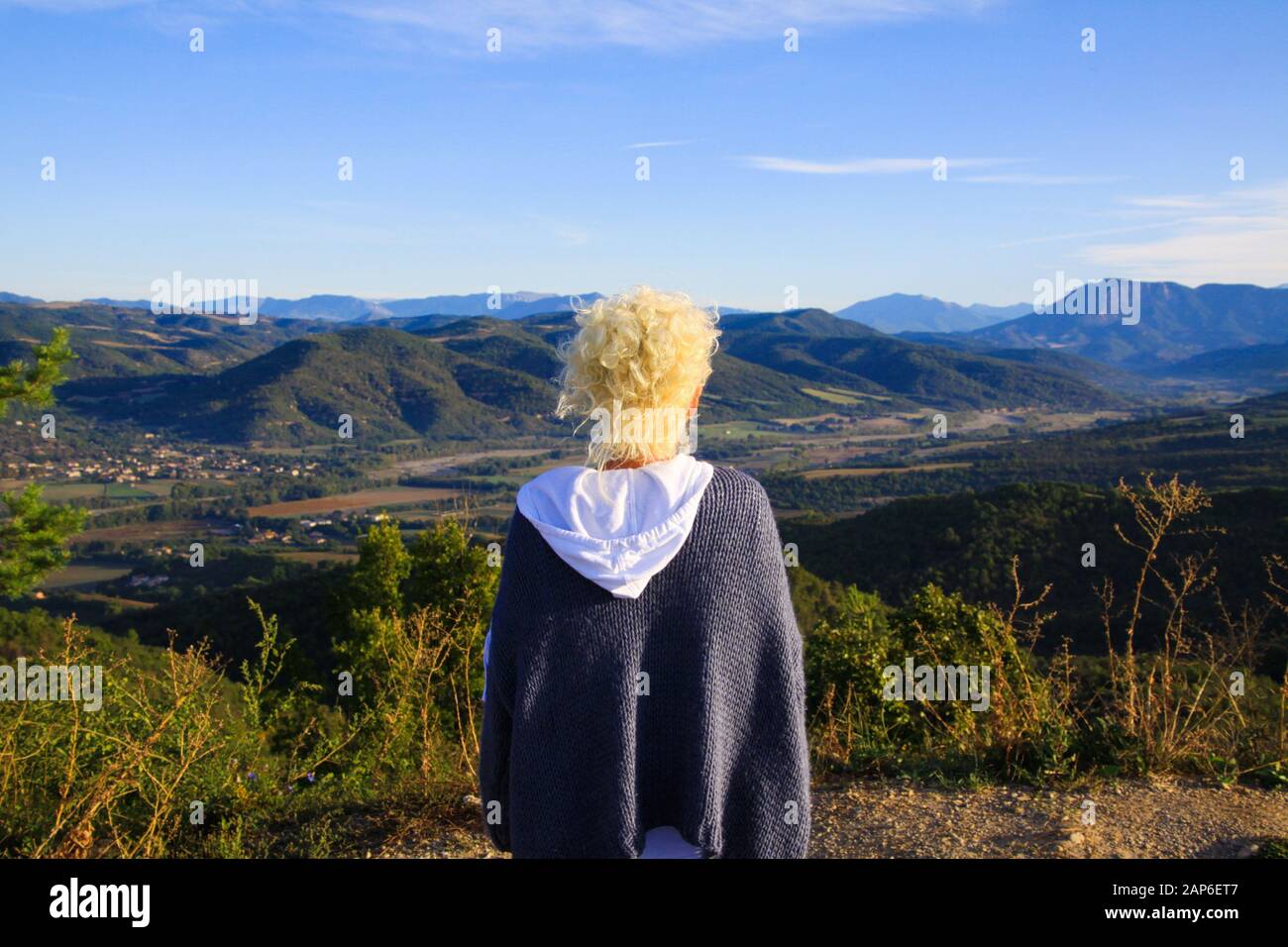 Vista su una donna isolata con capelli ricci biondi su un altopiano che guarda su una valle infinita con catena montuosa - Grand Canyon du Verdon, Francia Foto Stock