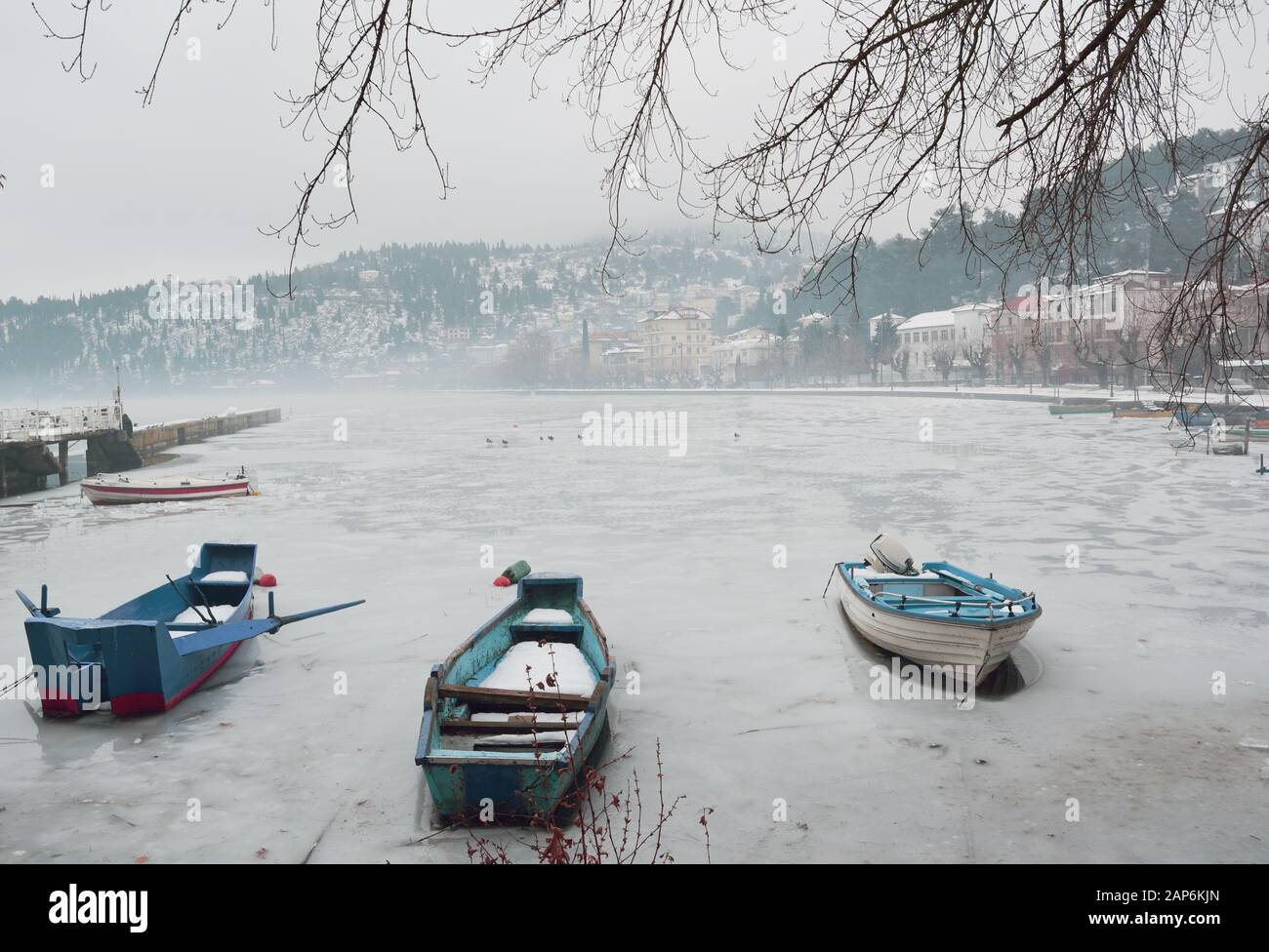 Barche in piccolo molo intrappolato nel lago ghiacciato di Orestiada a Kastoria, Grecia Foto Stock
