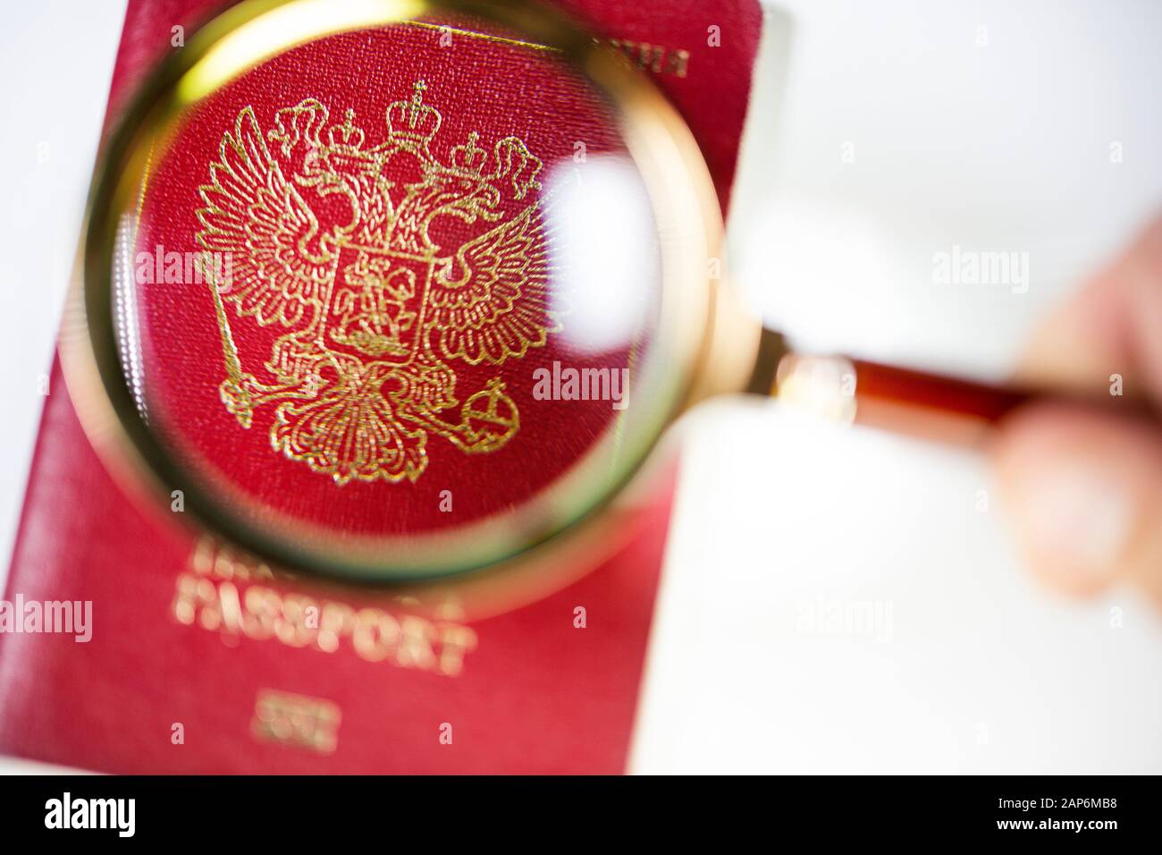Passaporto russo sotto una lente di ingrandimento su sfondo bianco Foto Stock
