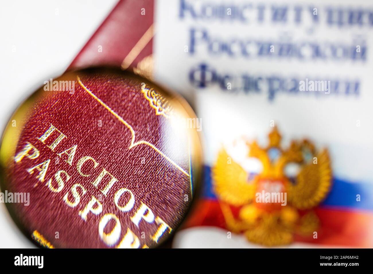 Passaporto russo sotto una lente di ingrandimento con la Costituzione della Federazione russa su sfondo bianco Foto Stock