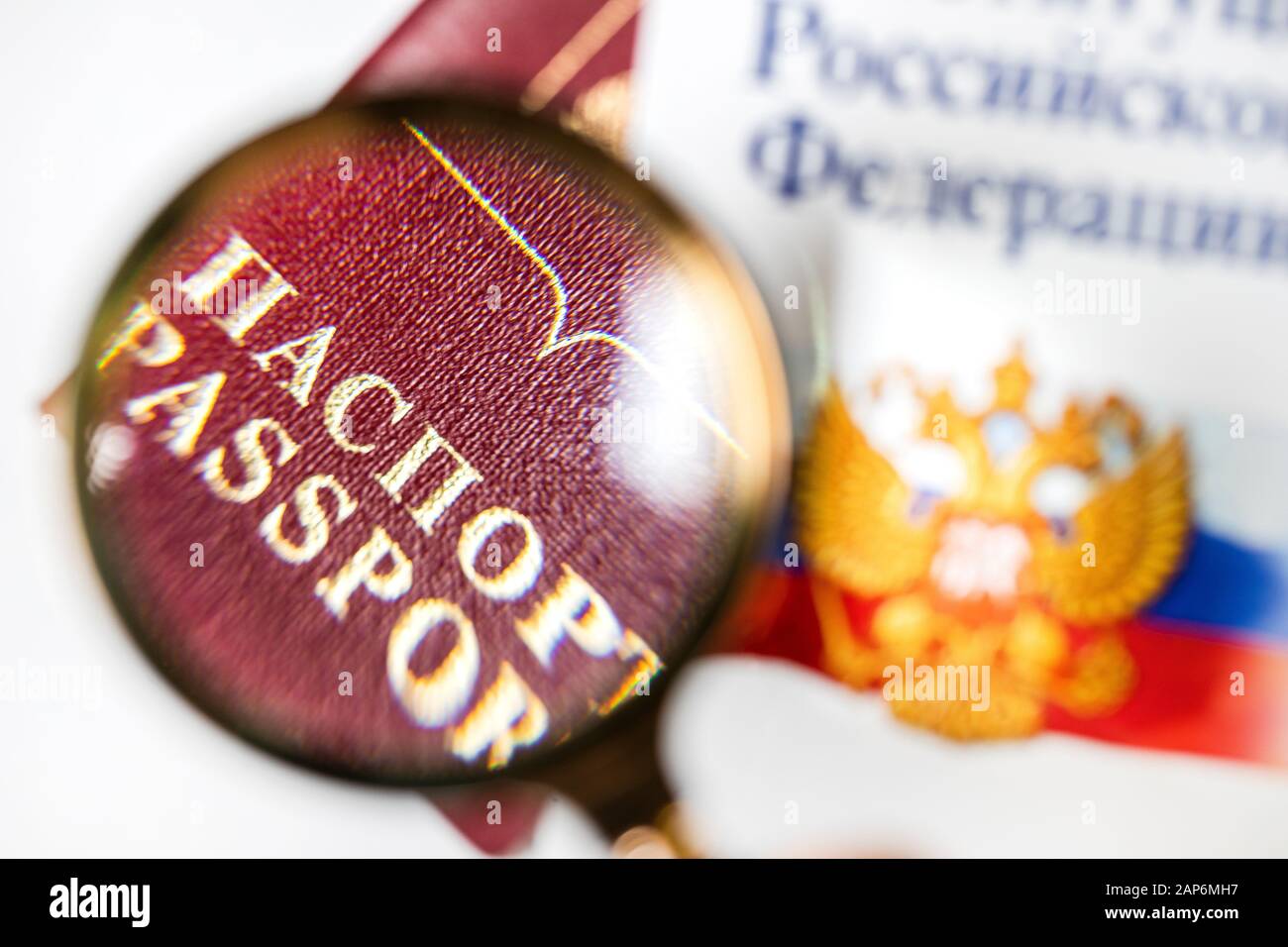 Passaporto russo sotto una lente di ingrandimento con la Costituzione della Federazione russa su sfondo bianco Foto Stock