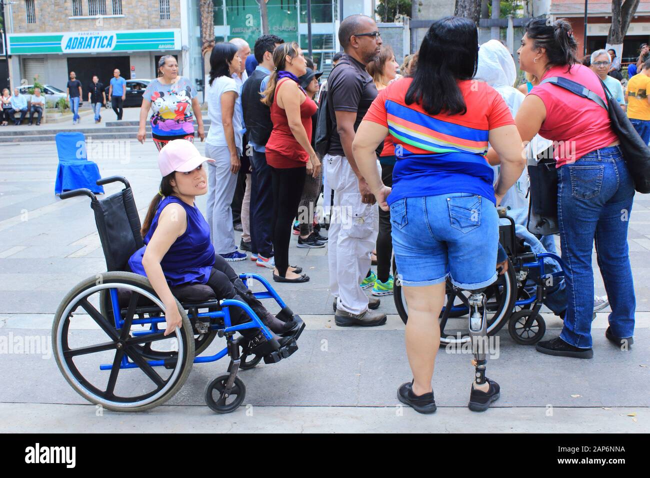 Disabilitare le persone con protesi della gamba vicino alle sedie a rotelle che si raccolgono nello spazio pubblico Foto Stock