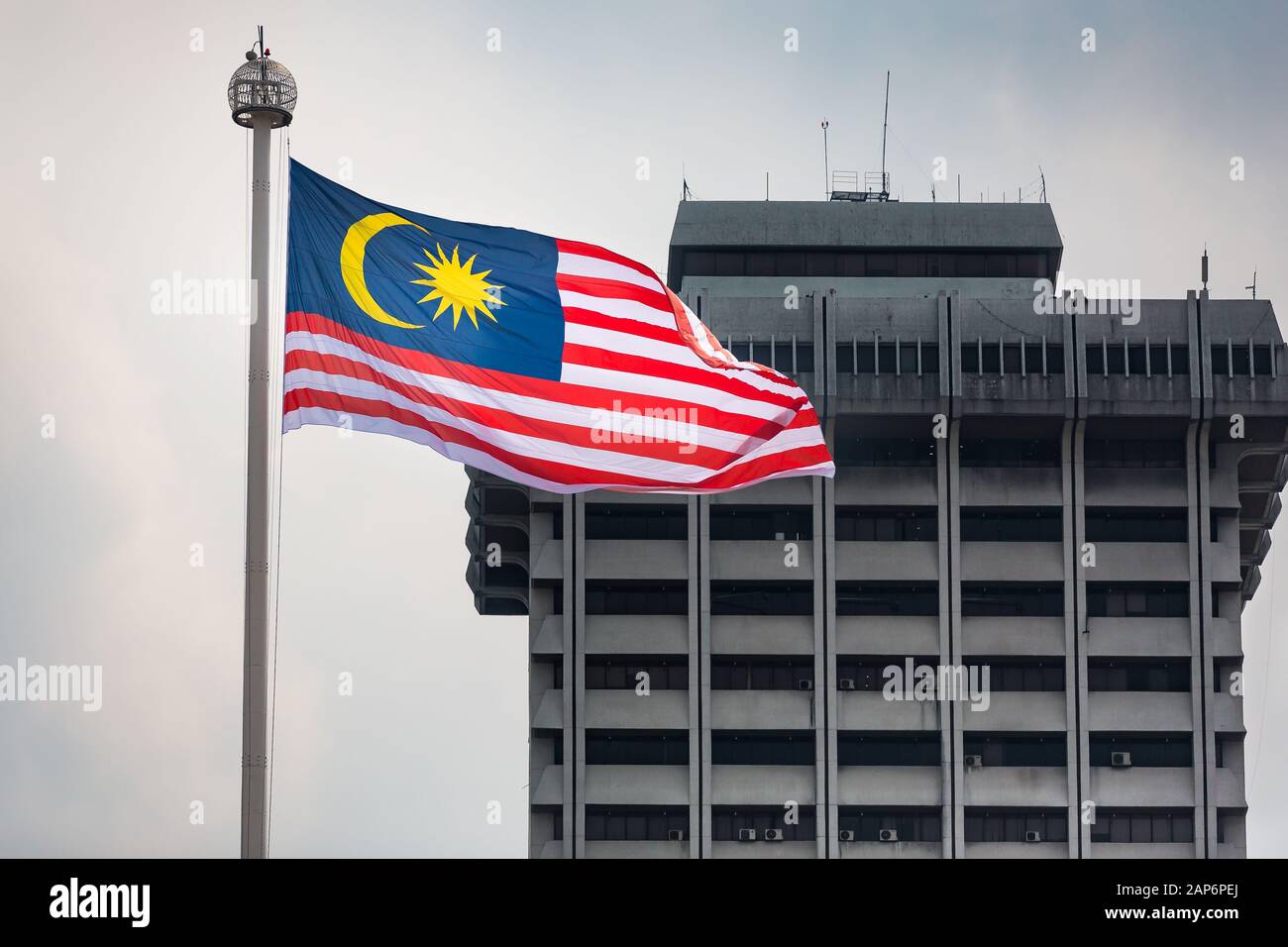 Grande bandiera malese che soffia in de wind con grande edificio sullo sfondo, Kuala Lumpur Foto Stock