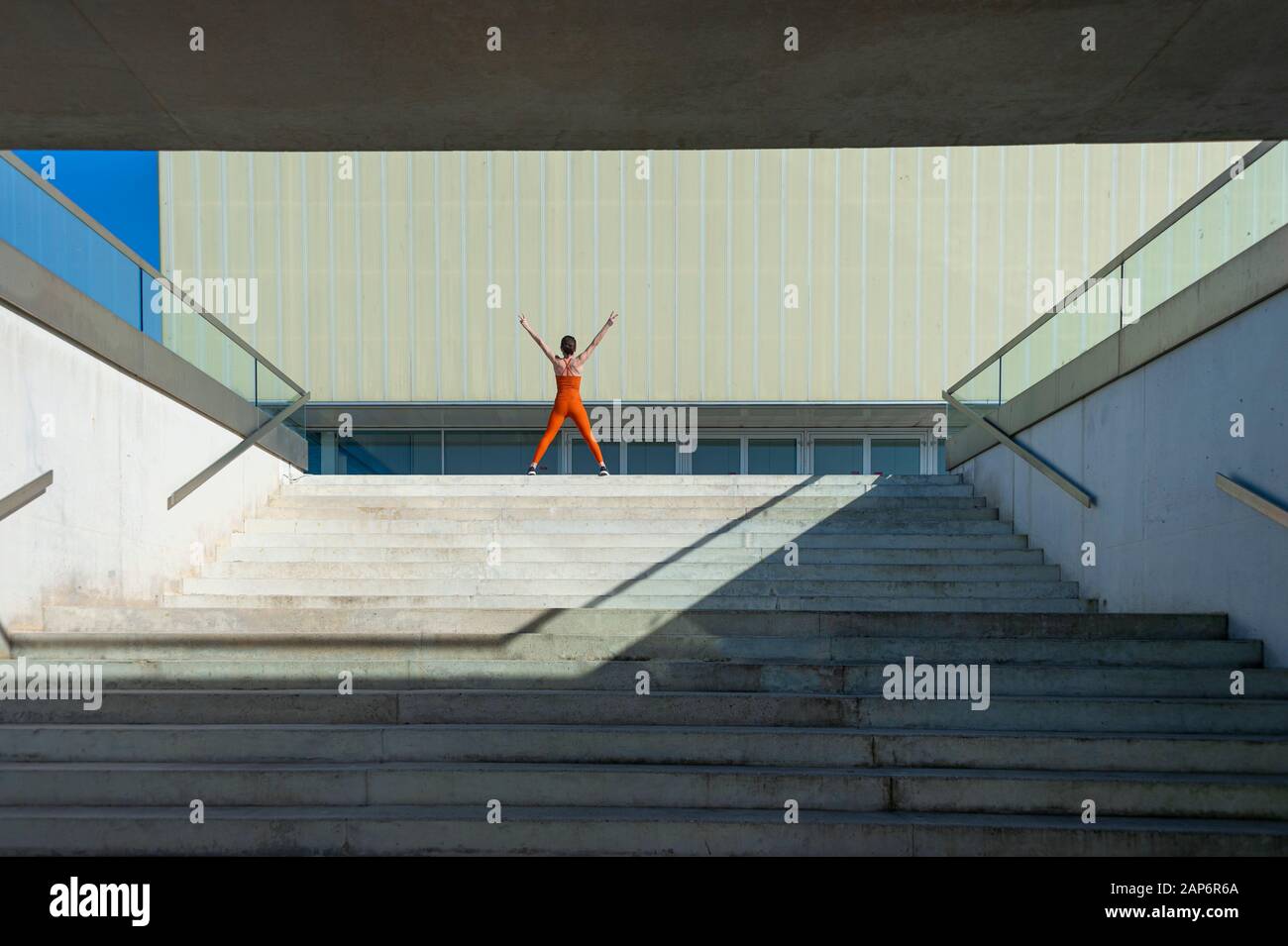Sportivo da donna nella parte superiore dei passi con le braccia sollevate, conseguimento. Foto Stock