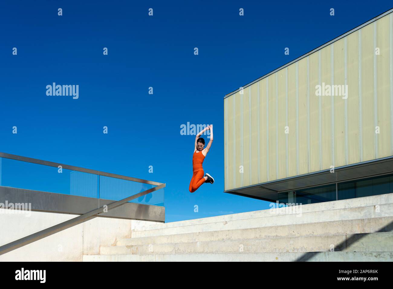 Donna che indossa abbigliamento sportivo arancione del salto in aria Foto Stock