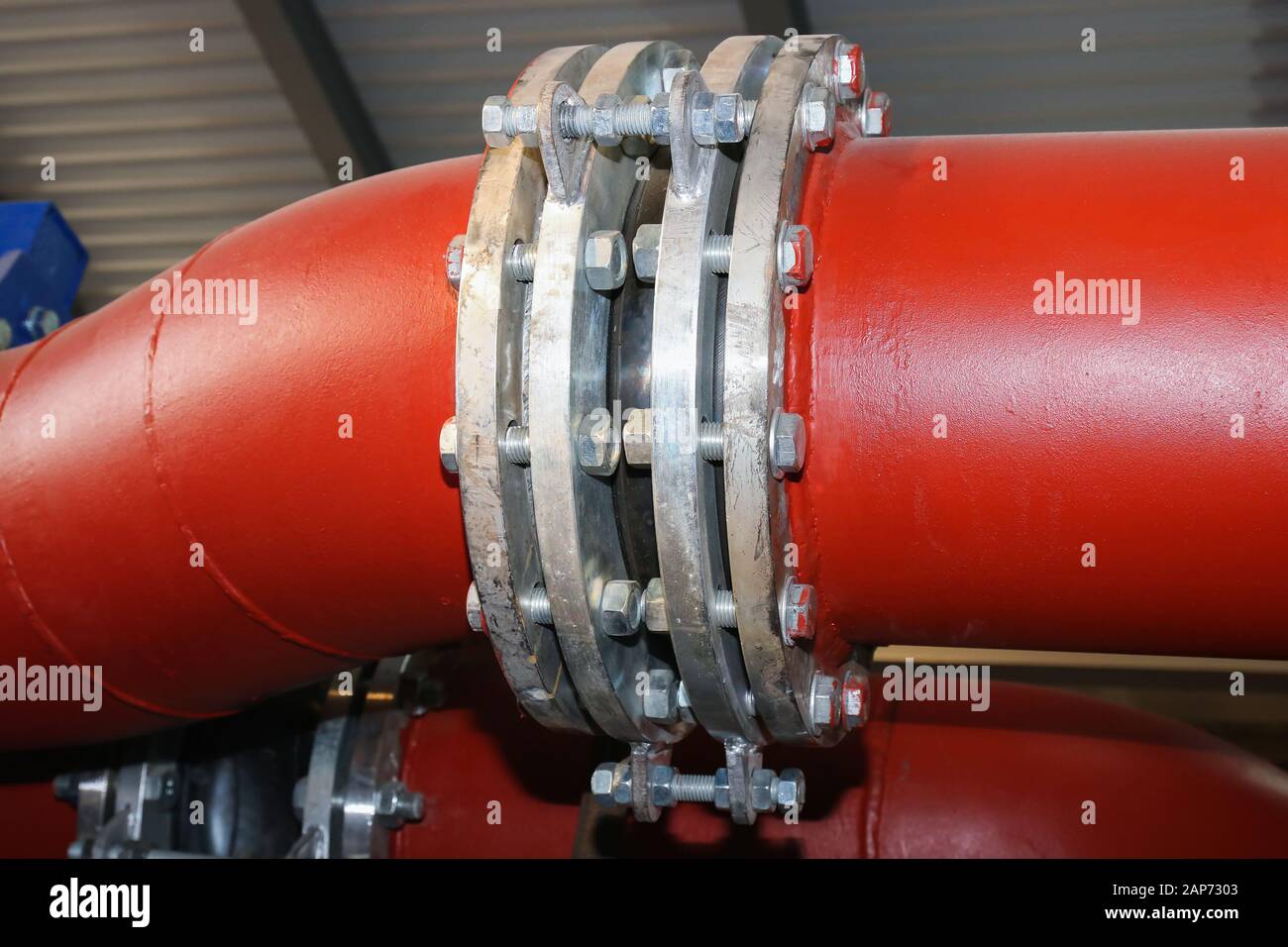 Giunto di espansione in gomma antivibrazioni nella tubazione nella linea di produzione industriale. Tubi rossi fuoco selettivo. Foto Stock