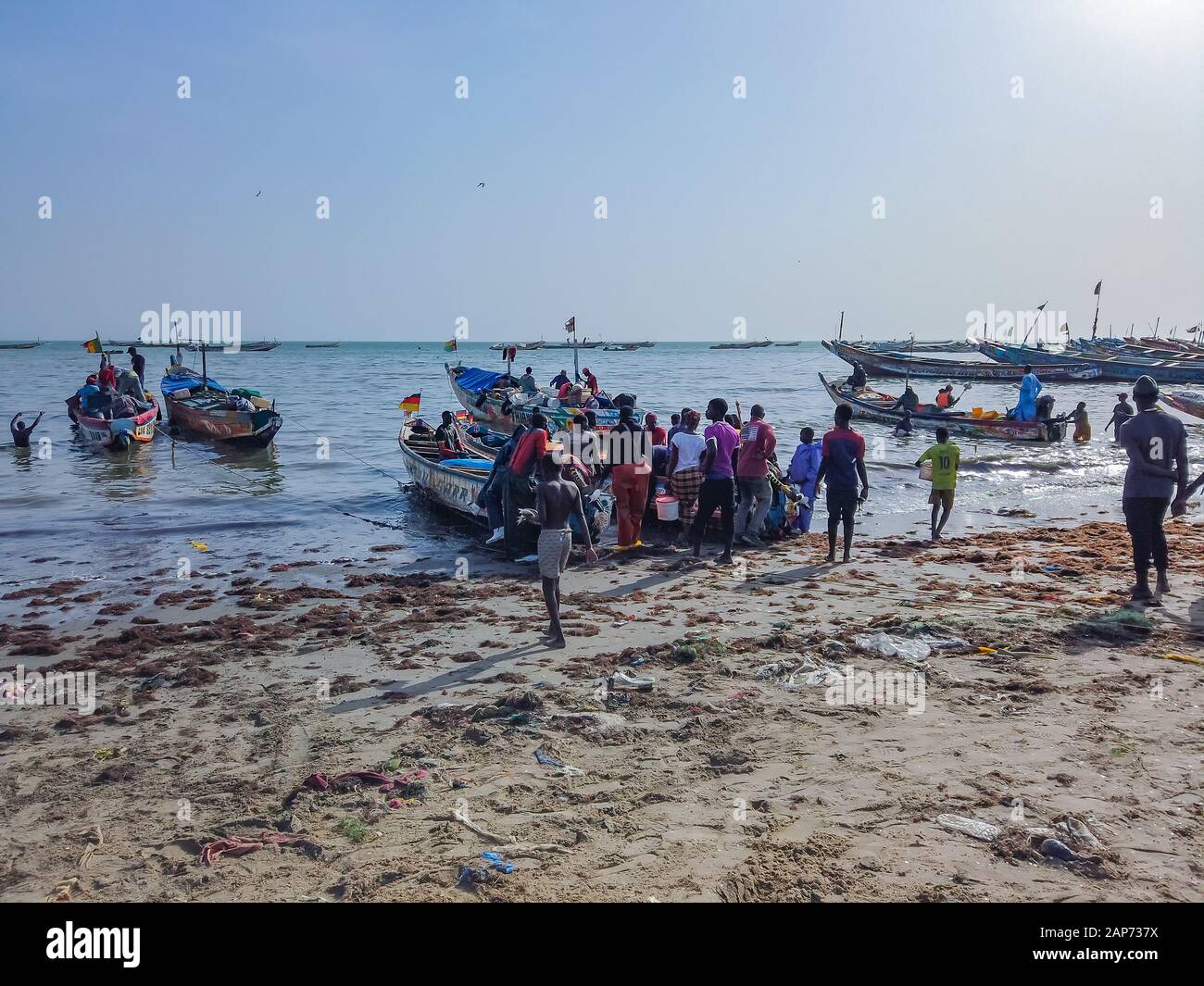 MBour, Senegal- 25 aprile 2019: Senegalesi non identificato gli uomini e le donne in attesa per i pescatori al mercato del pesce del porto della città nei pressi di Dakar. Vi Foto Stock