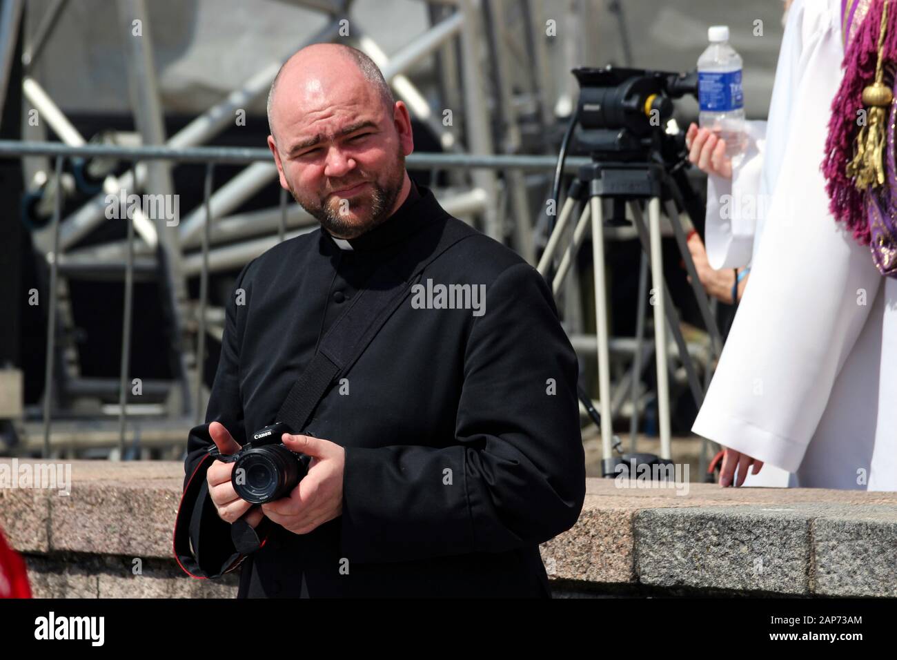 Sorridente sacerdote o pastore cattolico con telecamera DLSR a Vilnius, Lituania Foto Stock
