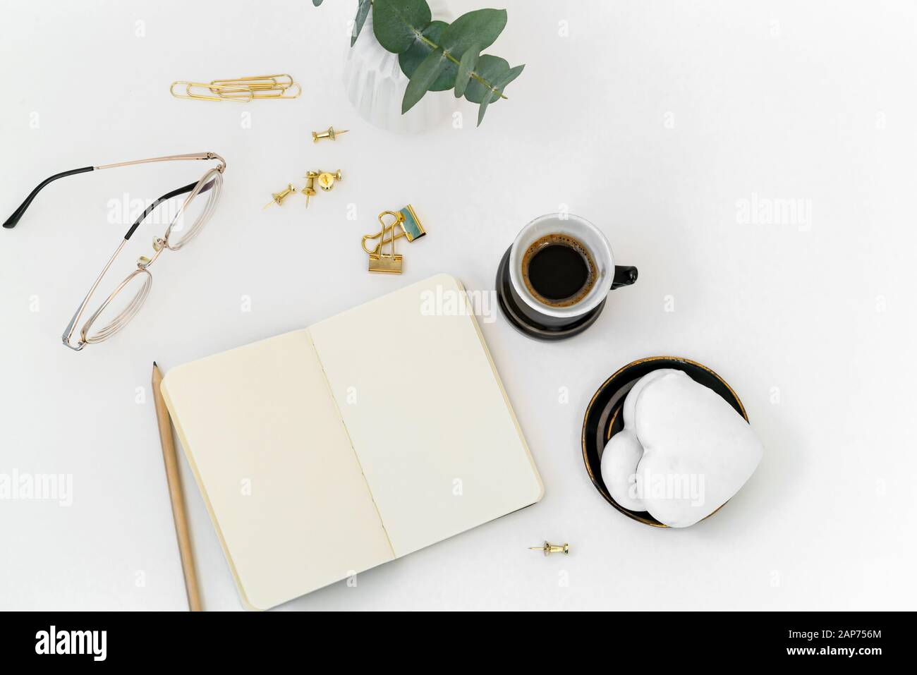 Composizione di San Valentino. Desktop femminile con tazza di caffè e piastra con biscotti allo zenzero a forma di cuore su sfondo bianco. Concetto di festa di San Valentino Foto Stock