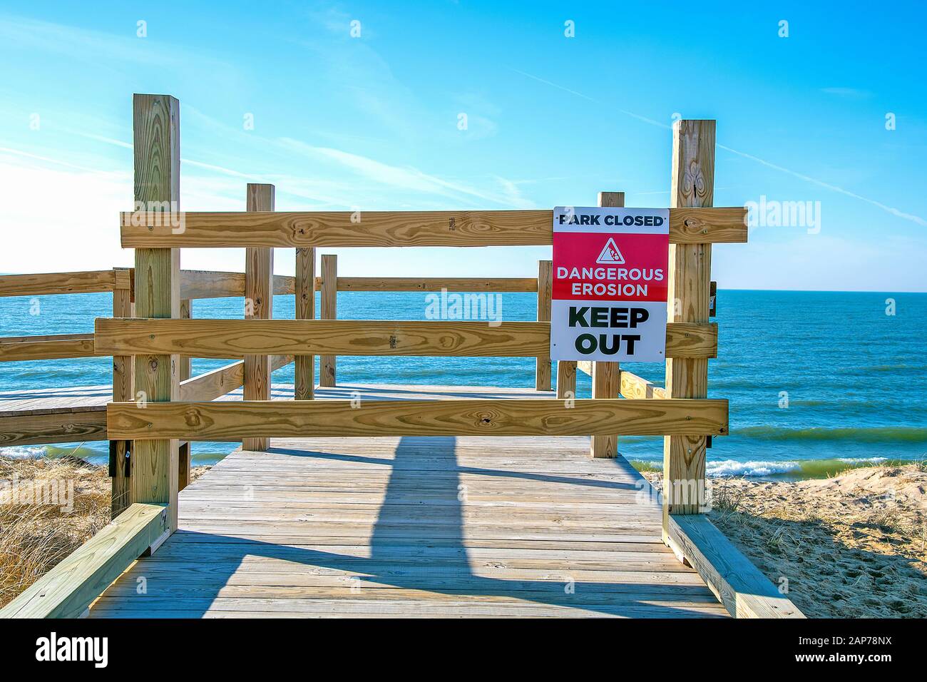 Cartello di avvertimento sull'erosione della spiaggia su un ponte di legno con sfondo del Lago Michigan Foto Stock