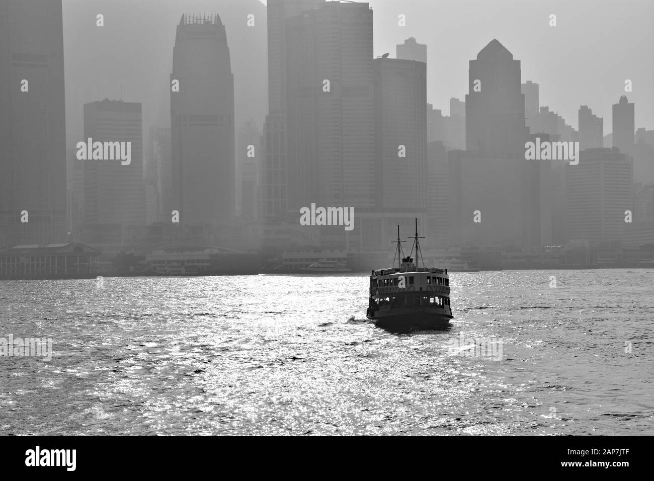 Immagine in bianco e nero dell'attraversamento dello Star Ferry tra il quartiere Centrale e la Penisola di Kowloon con una smog che pende sul centro di Hong Kong. Foto Stock
