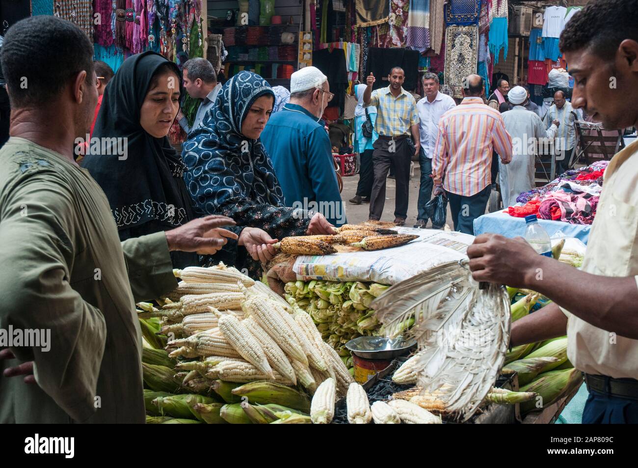 Una donna controlla le orecchie di mais in un mercato di strada lungo Muski nel quartiere Khan el-Khalili del Cairo, Egitto Foto Stock