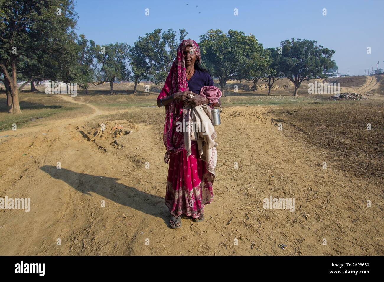 Un ritratto di una donna anziana fuori nella campagna rurale, in un sari rosso. A Allalabad, Uttar Pradesh, India. Foto Stock