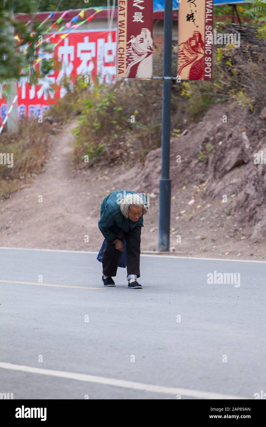 Una vecchia signora in eccessiva posizione di camminata di hunchback, la vita continua malgrado la difficoltà. Foto Stock