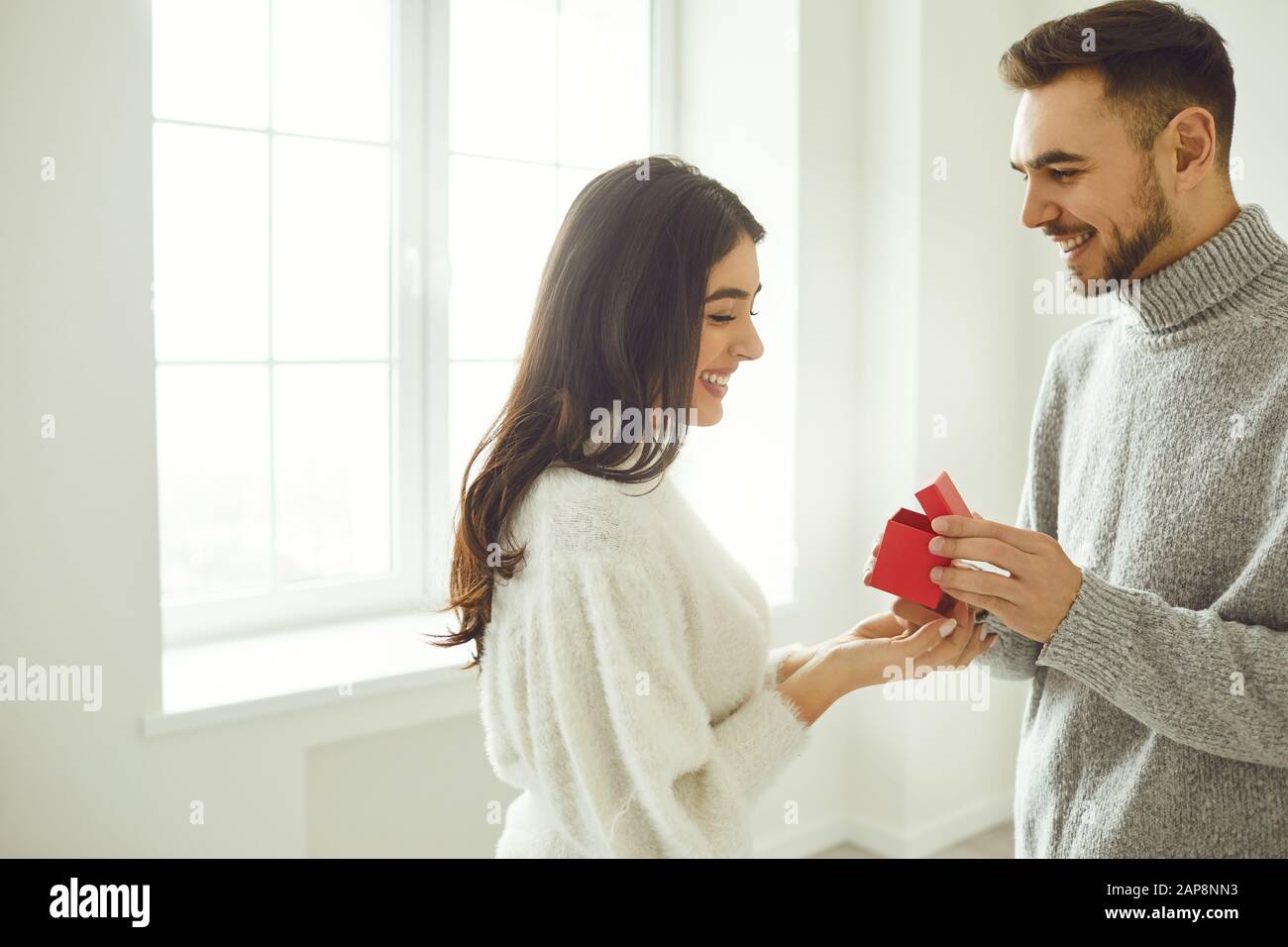 Il ragazzo fa una proposta di matrimonio alla ragazza. Sorridendo l'uomo dà un anello di proposta di matrimonio in camera. Foto Stock