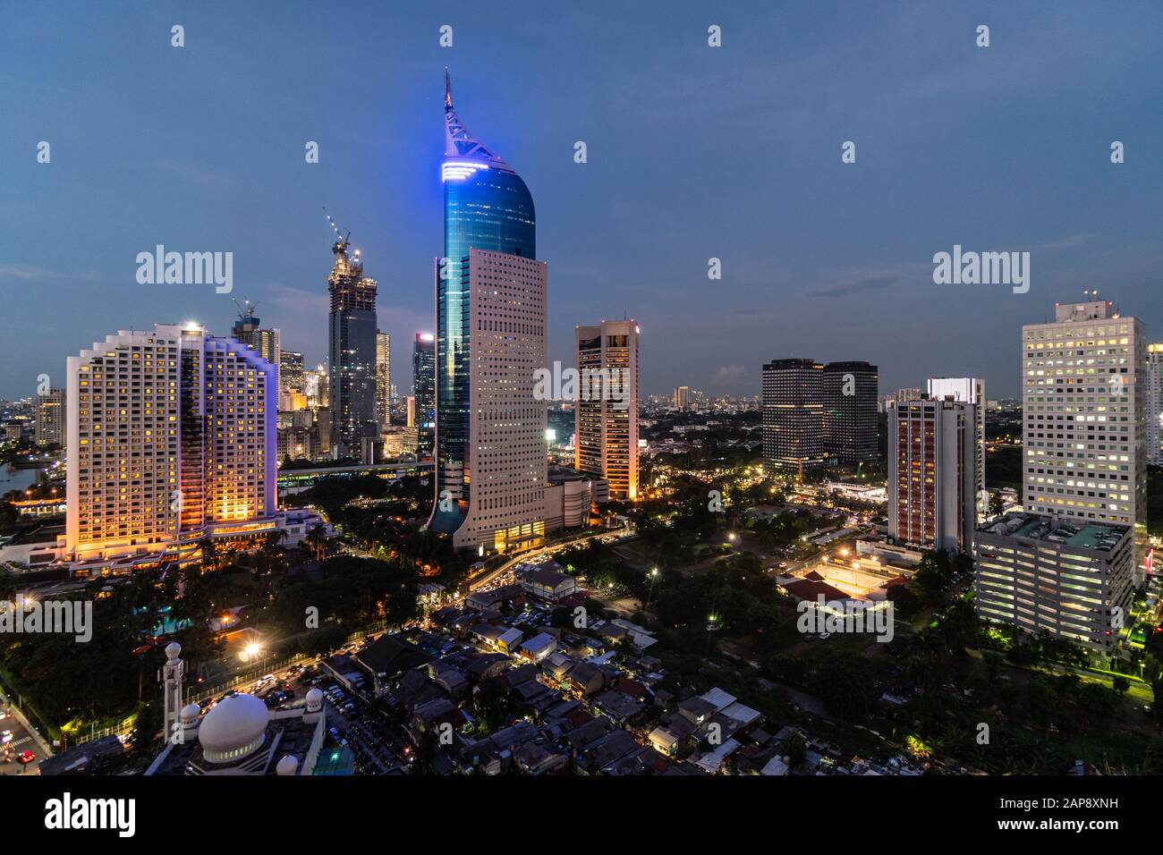 Incredibile crepuscolo sul centro di Giacarta distirct skyline, che contrasta con le basse case, nella capitale dell'Indonesia Foto Stock