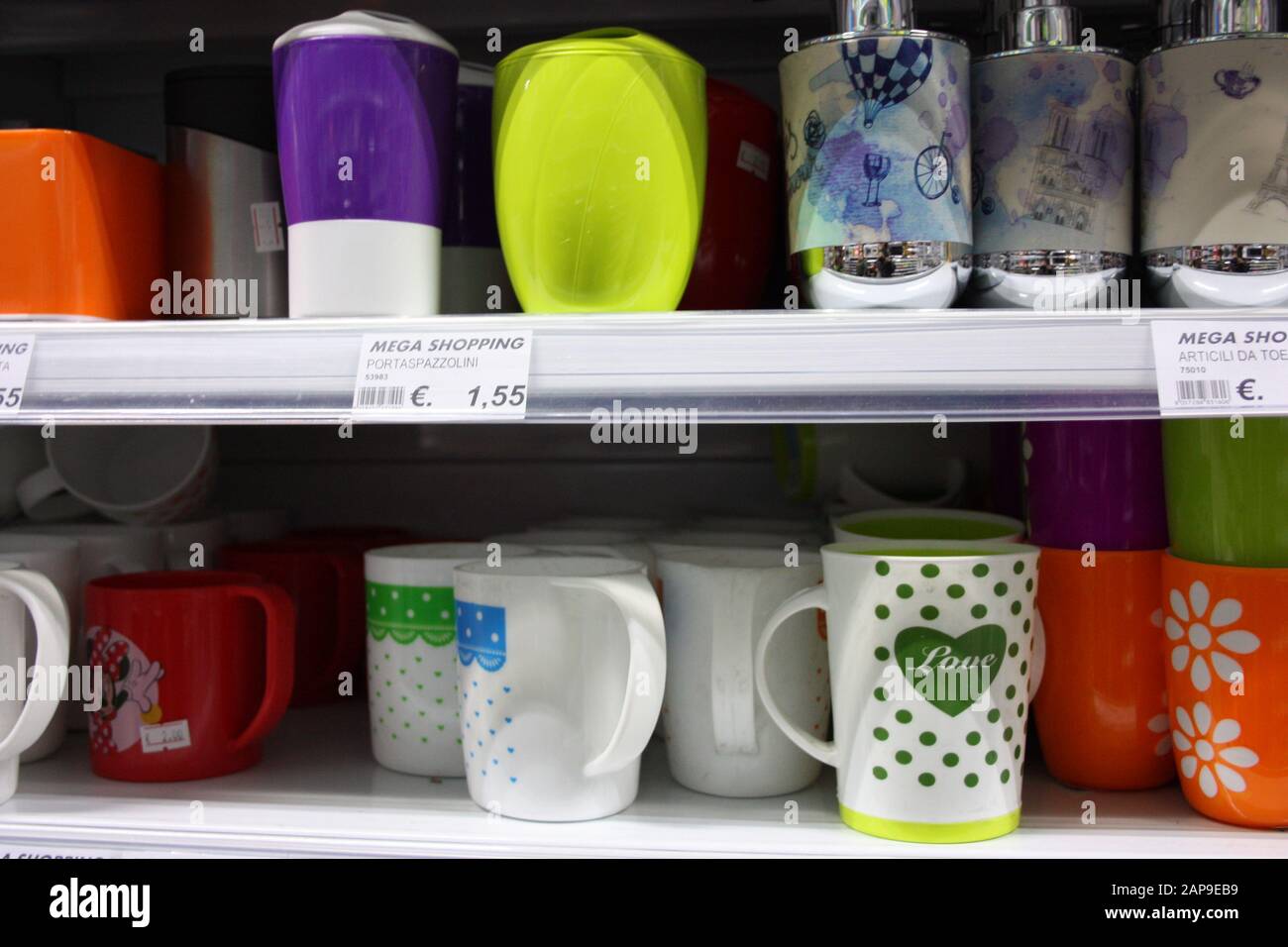 bicchieri colorati o contenitori di vari articoli domestici per qualsiasi uso domestico collocati su un ripiano in un negozio o scaffale in casa in italia Foto Stock