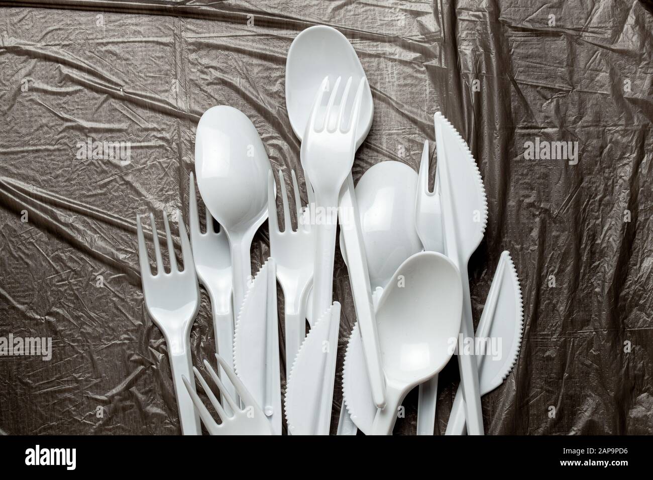 Posate di plastica, forchette, cucchiai e coltelli. Inquinamento  dell'ambiente con plastica e microplastics. In plastica nera dello sfondo  Foto stock - Alamy