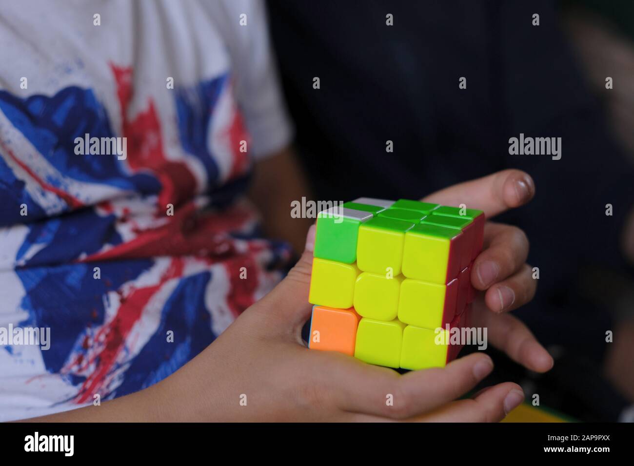 Cubo puzzle con facce multicolore nelle mani di un bambino di età scolastica Foto Stock
