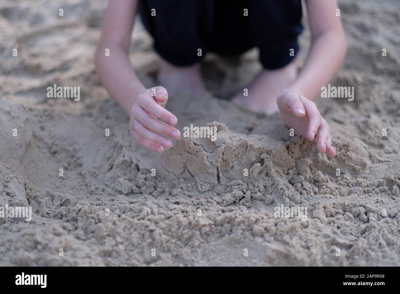 Mani di un ragazzo che gioca nella sabbia bagnata sulla spiaggia Foto Stock Mani di un ragazzo che gioca nella sabbia bagnata sulla spiaggia Foto Stock