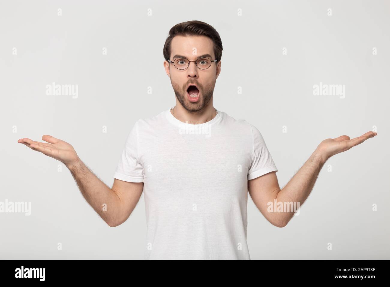 Confuso ragazzo millennial ha alzato le mani vicino gli spazi della copia per gli inserzionista. Foto Stock