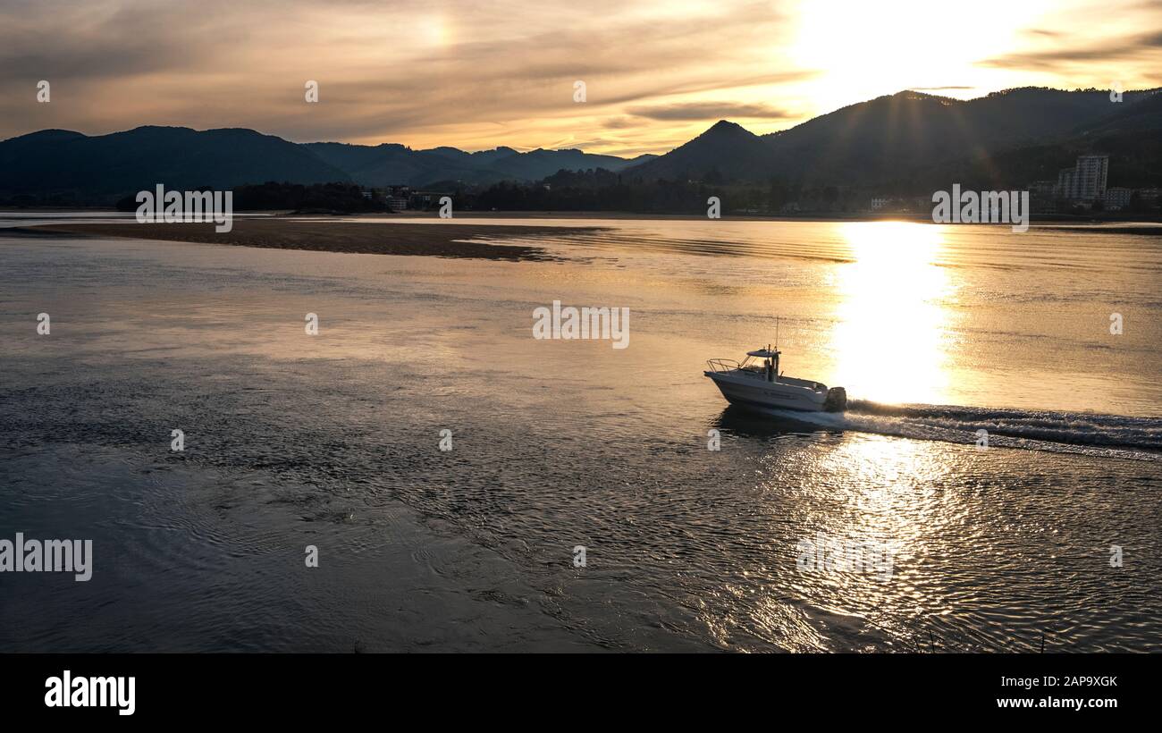 Barca ricreativa a Mundaca estuario al tramonto con Sukarrieta e montagne (Riserva della Biosfera di Urdaibai, Busturialdea, Biscay, Paesi Baschi, Spagna) Foto Stock