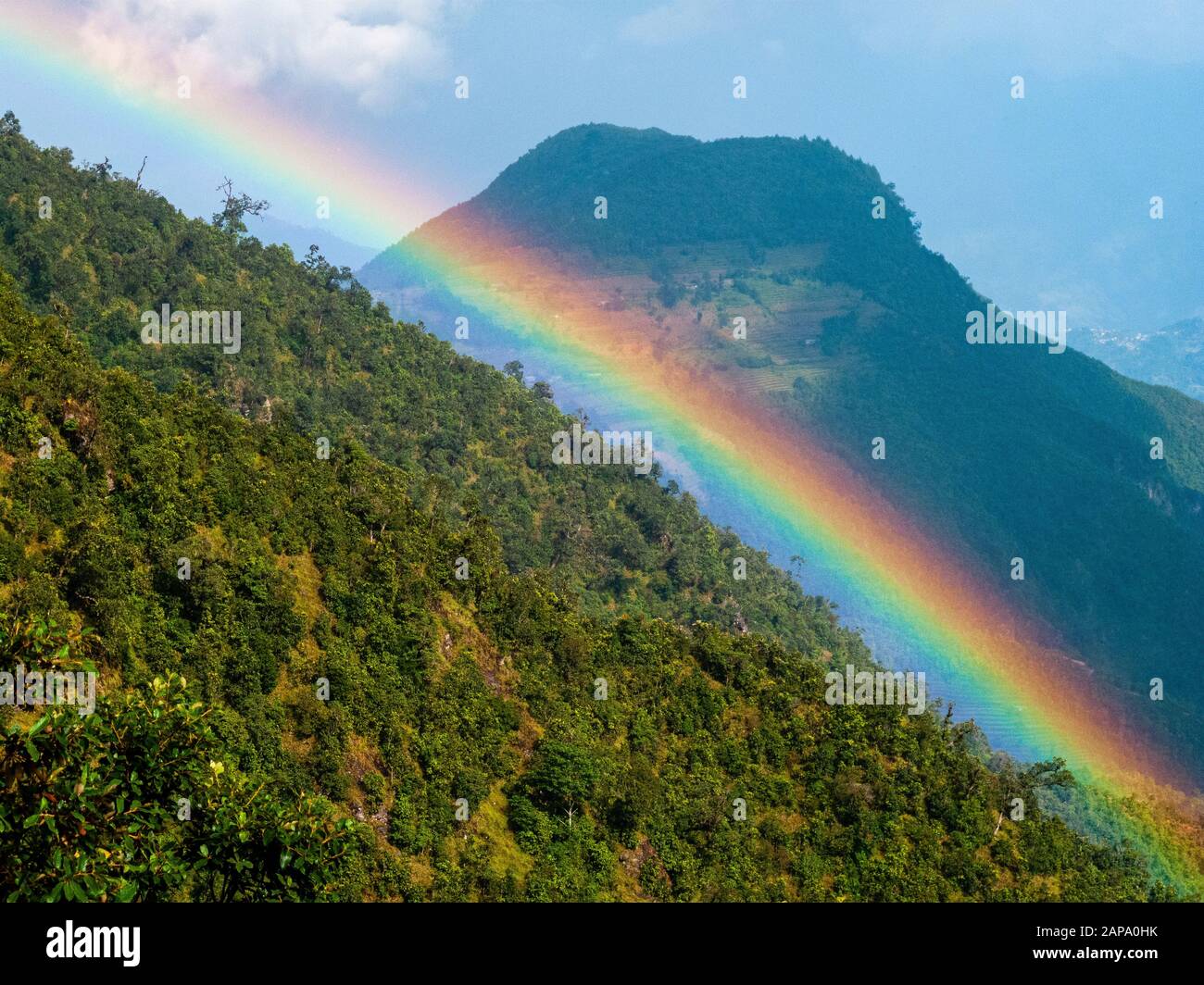 Arcobaleno incandescente lungo una cresta boscosa dopo una doccia a pioggia nella regione di Helambu Foto Stock