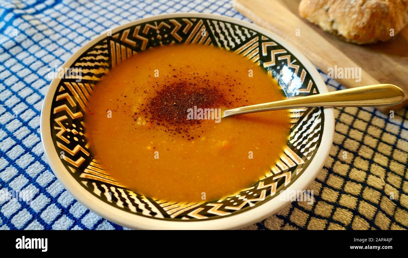 Una ciotola di zuppa vegana composta da patate dolci, zucca butternut, carote, lenticchie e peperoncino Foto Stock