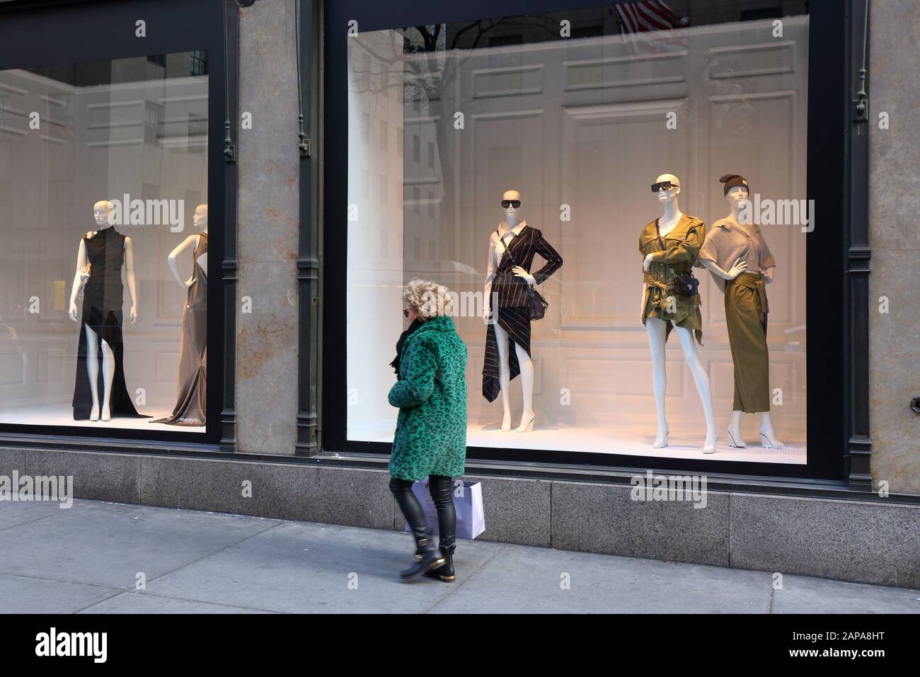 Una persona con un cappotto in pelliccia sintetica stampa leopardo verde e una borsa per lo shopping Bergdorf Goodman vicino alle finestre di Sak Fifth Avenue (21 gennaio 2020) Foto Stock