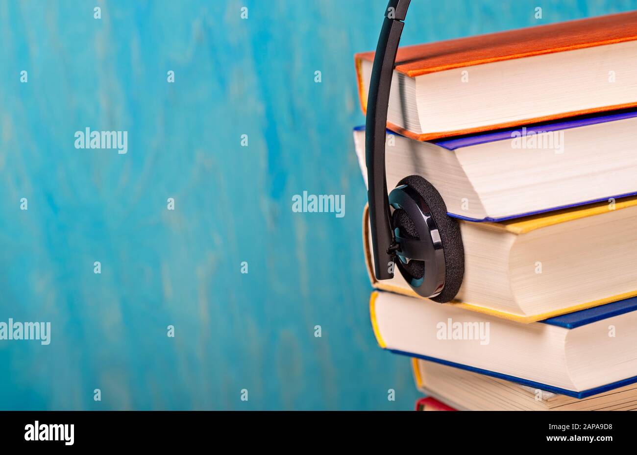 Cuffie con una pila di libri Foto Stock