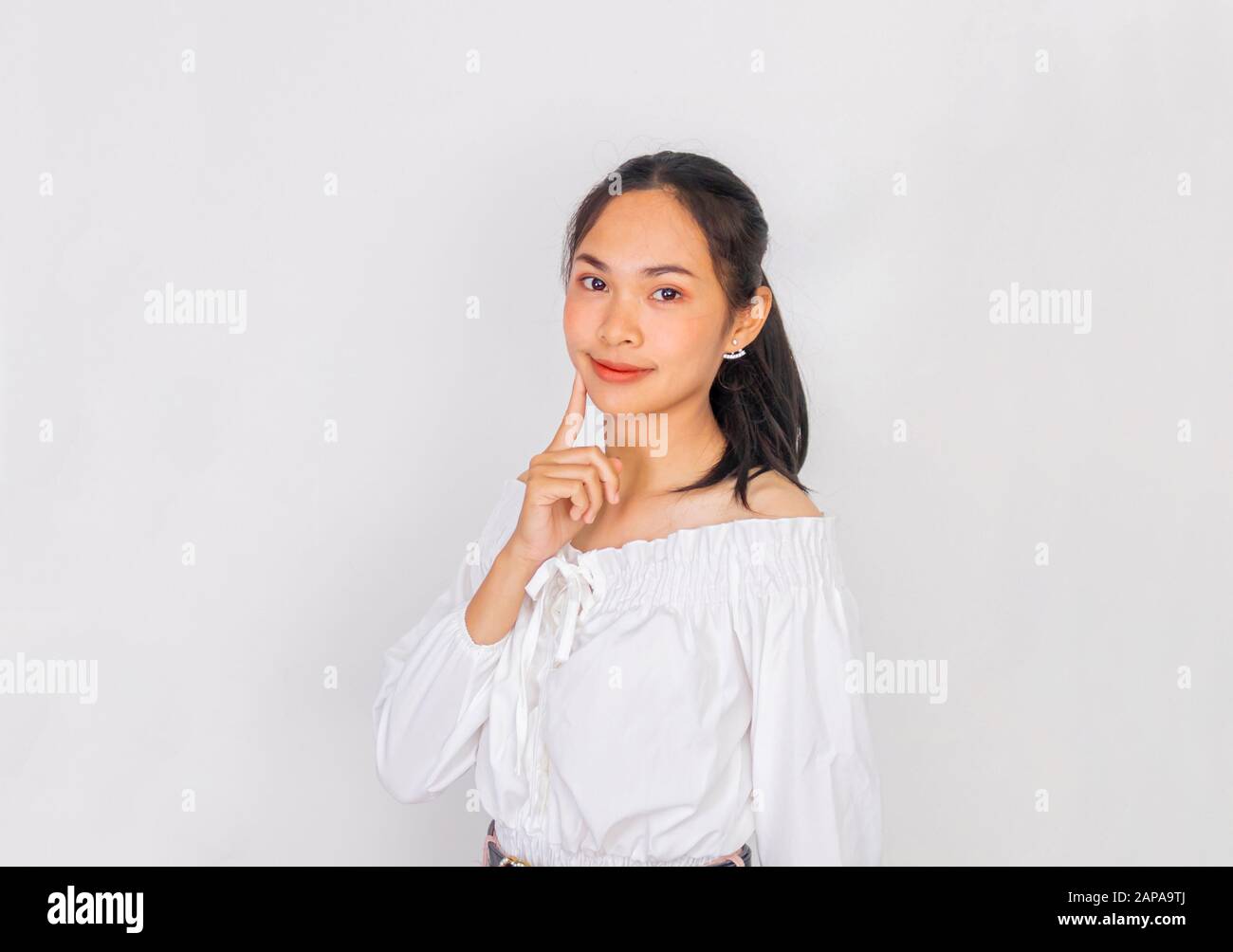 Una ragazza asiatica tocca il suo proprio sfondo bianco viso Foto Stock