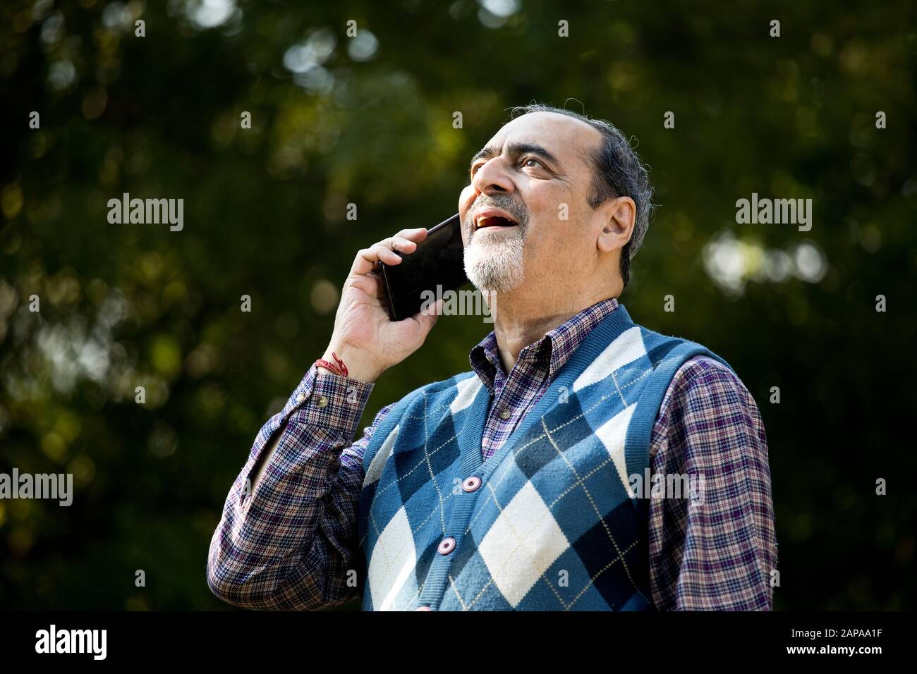 Buon uomo anziano che usa il telefono al parco Foto Stock