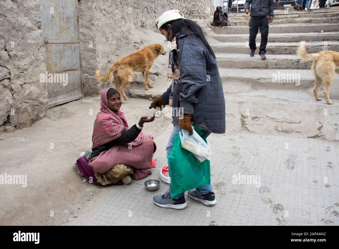 Jammu KASHMIR, INDIA - 19 MARZO : Viaggiatori donne thailandesi dare soldi alla vecchia vecchia donna indiana mendicante o intoccabile casta sedersi e mendicare nel mercato di le Foto Stock