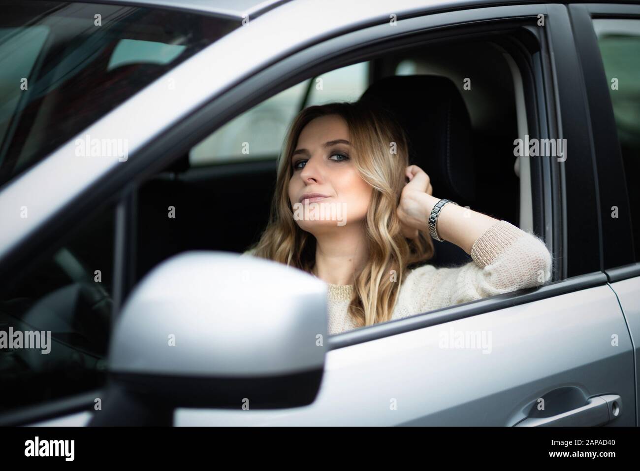 Bella donna bionda seduta in auto sul sedile di guida Foto Stock