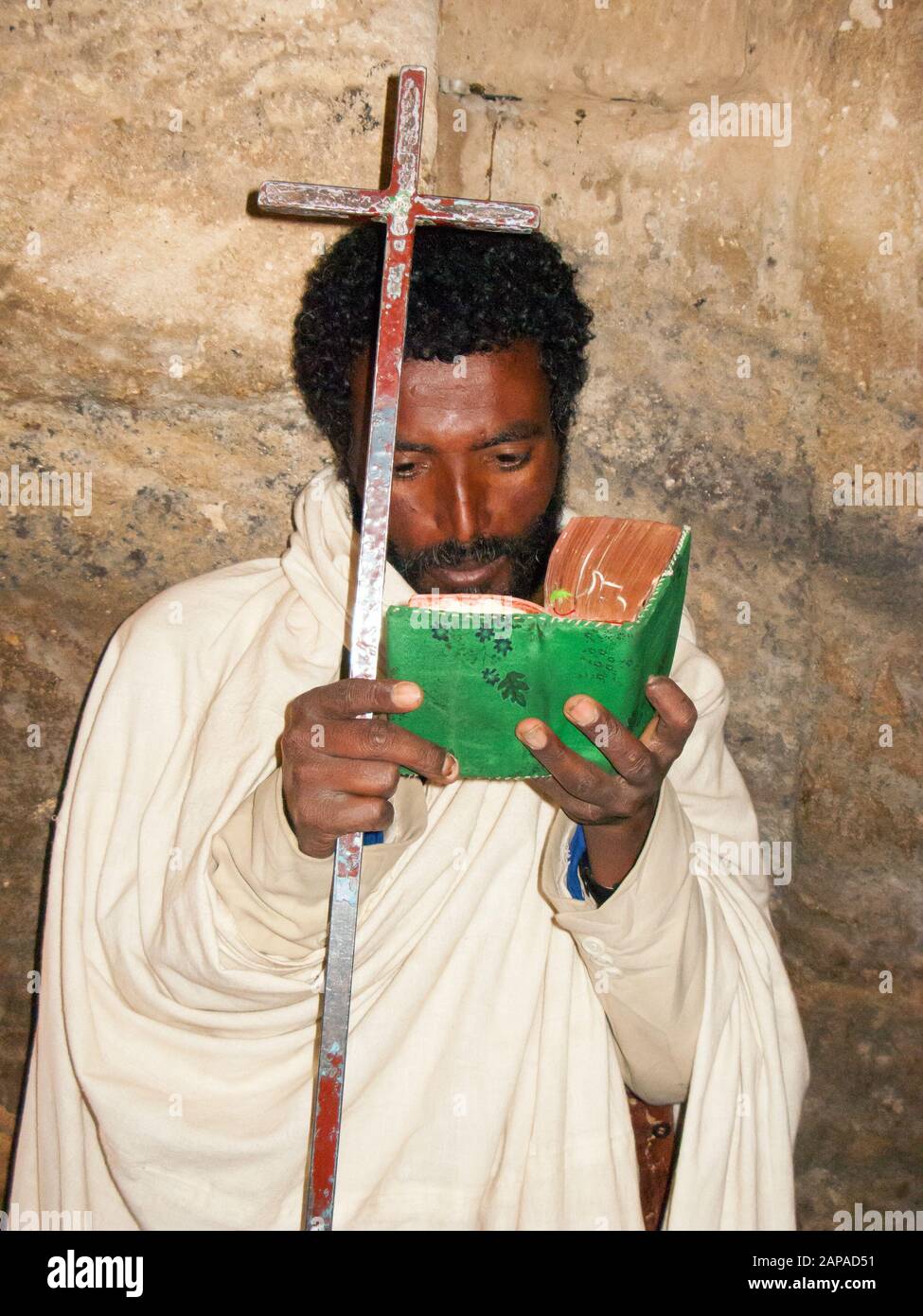 Il sacerdote della chiesa scavata nella roccia di Medhane Alem Adi Kasho legge la sua bibbia, Teka Tesfai, Tigray, Etiopia. Foto Stock