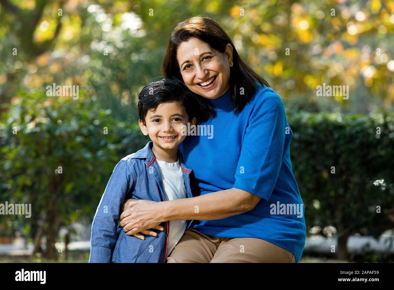 Nonna amorevole che abbraccia suo nipote al parco Foto Stock