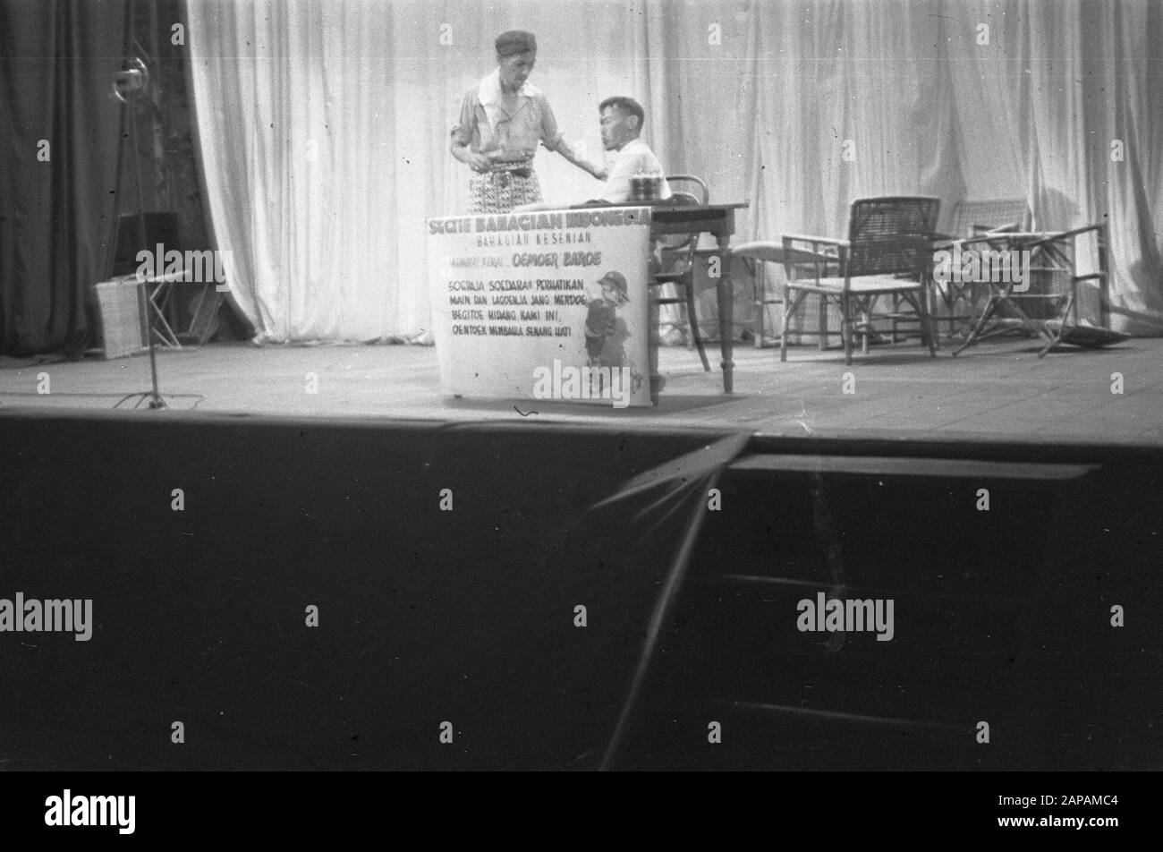 Spettacolo di cabaret. Due uomini indonesiani ad un tavolo. Uno si siede dietro il tavolo. Per la tavola un panno con iscrizione Sezione Bahagian Indonesia. Bahagian Kesenian. Memberi Kemal Umur Baroe. Sudaja Sudara2 Perhatikan/Main Dan Lagoenja Jang Merdoe/ Begitoe Hidang Kami Ini/ Oentoek Membagla Senang Hati Data: 1947/01/01 Ubicazione: Indonesia, Indie Orientali Olandesi Foto Stock