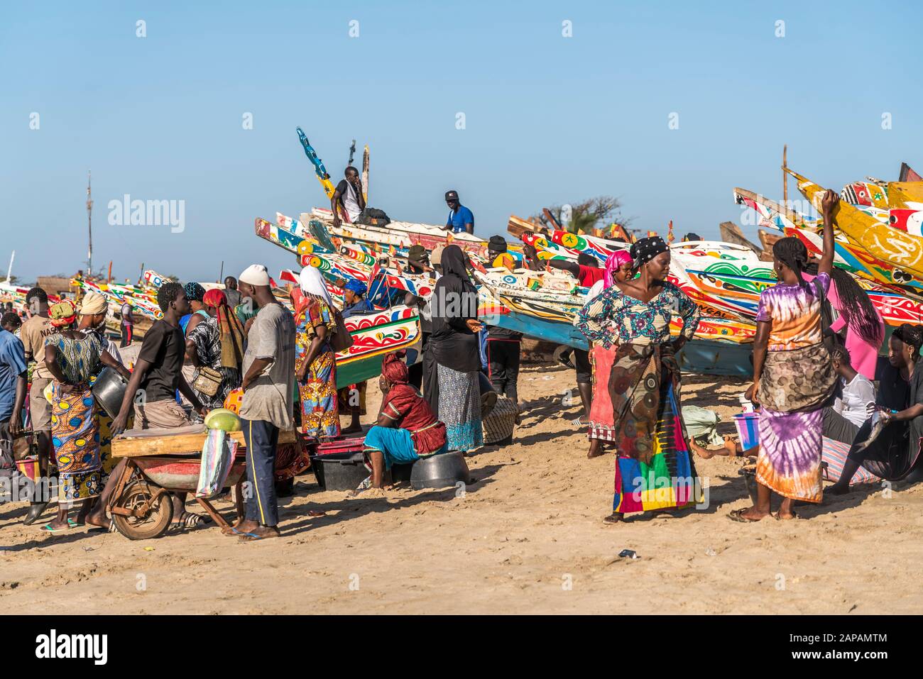 Bunte Kleider und Boote auf dem Fischmarkt a Tanji, Gambia, Westafrika | vestiti colorati e barche al mercato del pesce, Tanji, Gambia, Africa occidentale Foto Stock