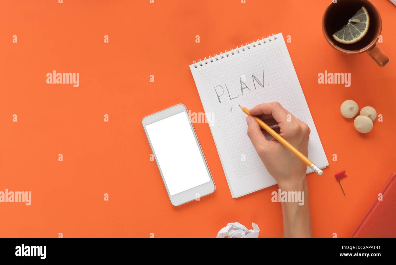 Colori moderni tavolo scrivania da ufficio con notepad smartphone e altri materiali con una tazza di tè. Vuoto nella pagina del blocco note per inserire testo nel mezzo. Parte superiore Foto Stock