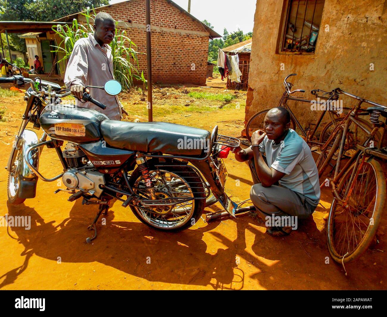Un meccanico ripara questa boda boda (moto taxi) sulla strada nel distretto rurale di Jinja, Uganda. Foto Stock
